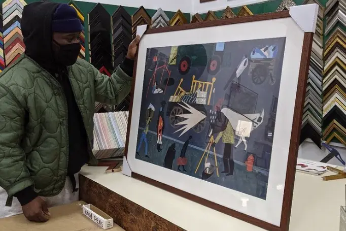 A man looks at his newly framed Jacob Lawrence painting print